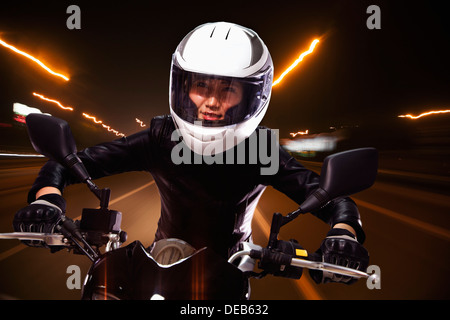 Young woman riding a motorcycle through the streets of Beijing, light trails Stock Photo