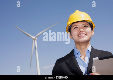 Young smiling female engineer checking wind turbines on site Stock Photo