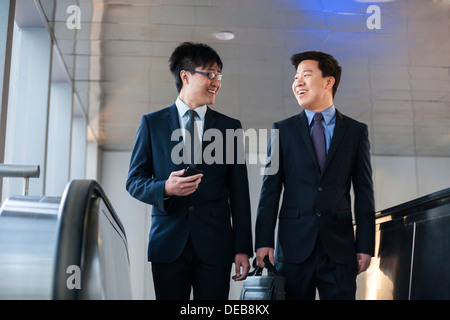 Two smiling businessmen coming up the escalator together Stock Photo