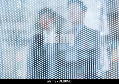 Two businessmen behind a glass wall looking out, unrecognizable faces Stock Photo