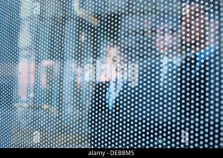 Three business people behind a glass wall looking out, unrecognizable faces Stock Photo