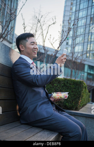 Smiling businessman on lunch texting on his mobile phone outdoors Stock Photo