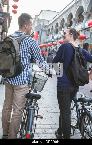 Young man and woman with bicycles, walking down street. Stock Photo