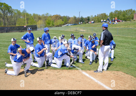 coach discusses strategy with his team at a high school baseball game Stock Photo