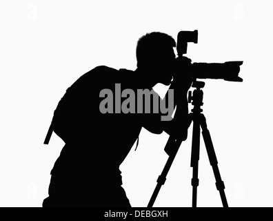Silhouette of man taking pictures with camera on tripod. Stock Photo