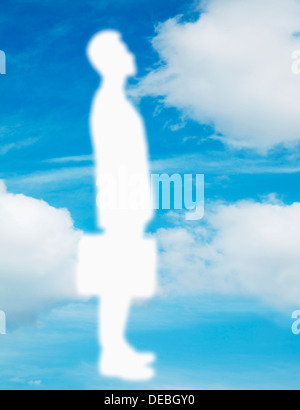 Silhouette of businessman holding a briefcase with a blue sky and clouds behind him Stock Photo