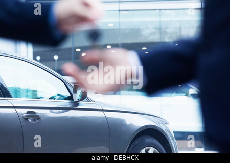 Car salesman handing over the keys for a new car to a young businessman, close-up Stock Photo