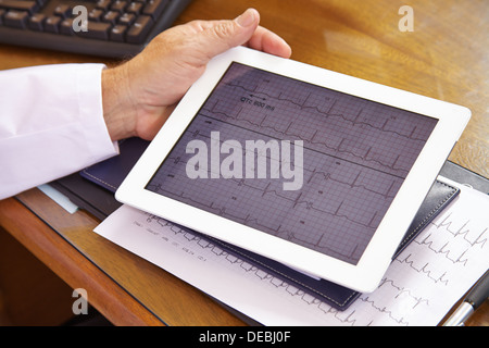 Doctor looking at ECG on a tablet computer in his office Stock Photo