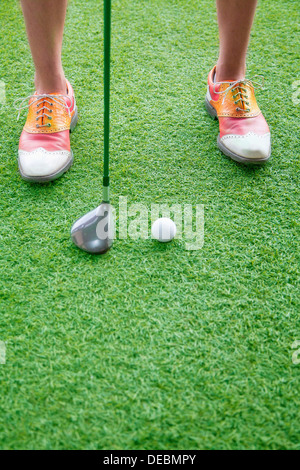 Close up on feet and golf club getting ready to hit a golf ball Stock Photo