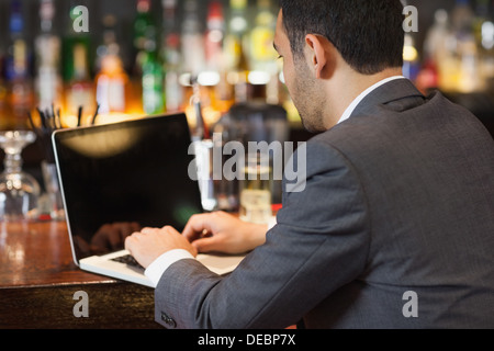 Handsome businessman working on his laptop while having a drink Stock Photo