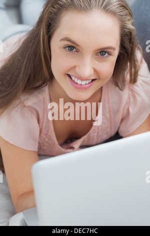 Woman lying on sofa with laptop Stock Photo