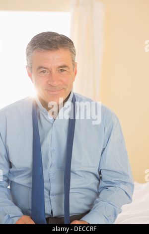 Happy man looking at camera sitting on a bed Stock Photo