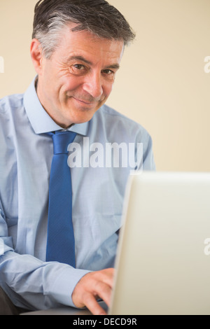 Pleased man using a laptop sitting on bed Stock Photo