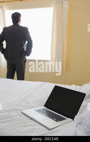 Man standing by the window looking out Stock Photo