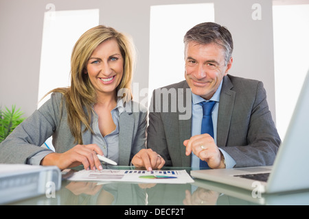 Two pleased business people smiling analysing a graphic Stock Photo