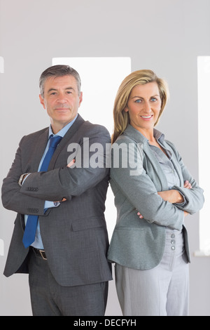 Two content businesspeople looking at camera standing back-to-back Stock Photo