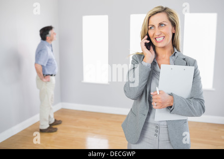 Cheerful realtor calling someone with her mobile phone Stock Photo