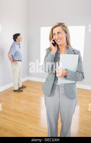 Smiling realtor calling someone with her mobile phone Stock Photo