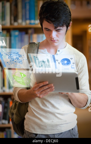Serious handsome student working on his futuristic tablet pc Stock Photo