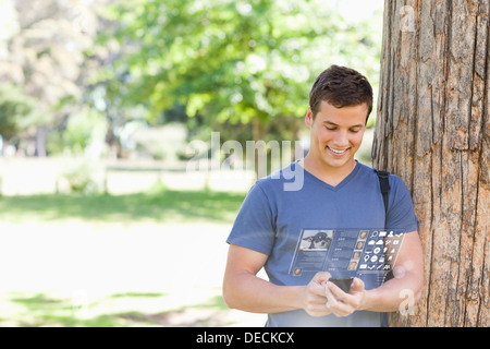 Cheerful handsome student using his digital smartphone Stock Photo
