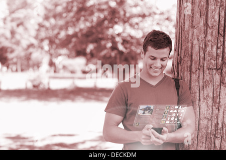 Smiling handsome student using his digital phone Stock Photo
