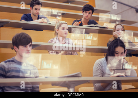 Concentrated students in lecture hall working on their futuristic tablet Stock Photo