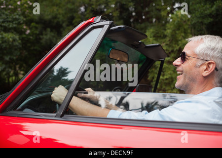 Smiling handsome man driving red convertible Stock Photo