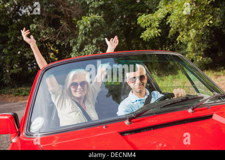 Mature couple in red cabriolet cheering at camera Stock Photo