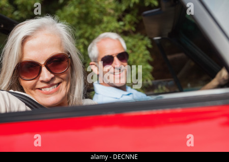 Side view of cheerful mature couple driving red cabriolet Stock Photo
