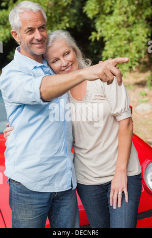 Smiling mature couple posing by their red convertible Stock Photo