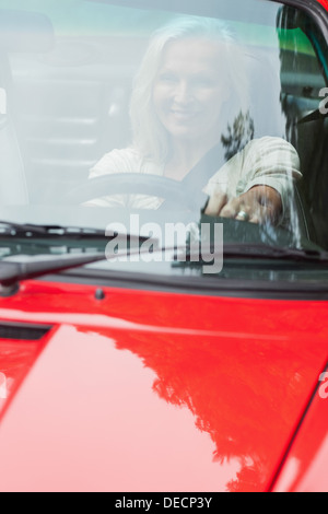 Smiling mature woman driving red cabriolet Stock Photo