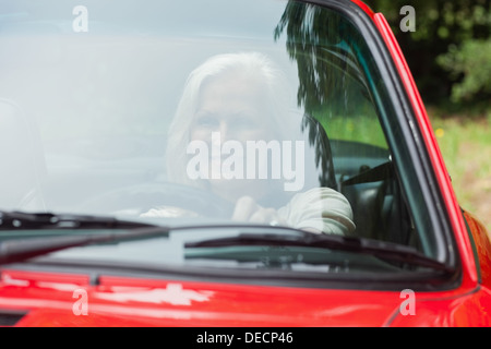 Cheerful mature woman driving red cabriolet Stock Photo