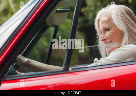 Cheerful mature woman driving red convertible Stock Photo