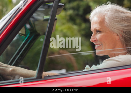 Smiling mature woman driving red convertible Stock Photo