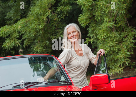 Cheerful mature woman getting off her convertible Stock Photo
