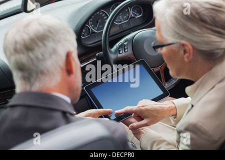 Mature partners working together on tablet in classy convertible Stock Photo