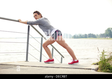 Healthy female runner stretching during running or jogging workout outdoor. Wearing fitness clothing. Stock Photo