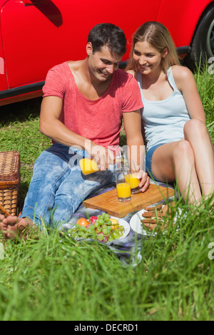 Happy couple sitting on the grass having picnic together Stock Photo