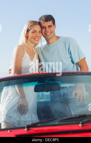 Smiling couple standing in red cabriolet posing Stock Photo