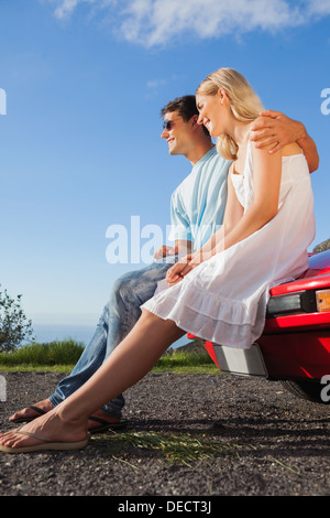 Cheerful couple sitting on their cabriolet car hood Stock Photo