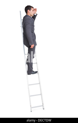 Young businessman standing on ladder looking away Stock Photo