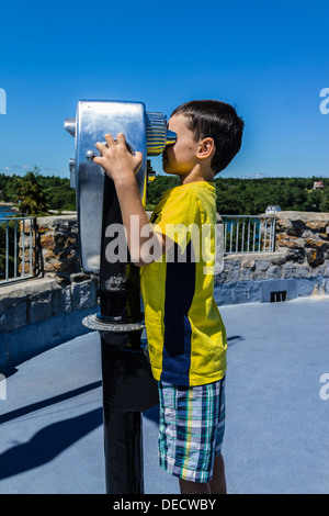 A boy looking through a coin-operated public binocular at Fort Frederick/Fort William Henry historic site in Maine. Stock Photo