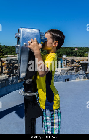 A boy looking through a coin-operated public binocular at Fort Frederick/Fort William Henry historic site in Maine. Stock Photo