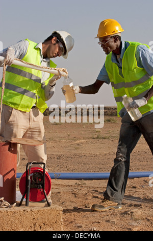 Taking water samples from bore hole, to test quality on industrial gold mining complex, Mauritania, NW Africa Stock Photo