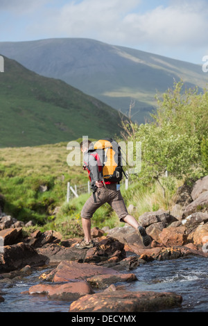 Man crossing a river on a hike Stock Photo