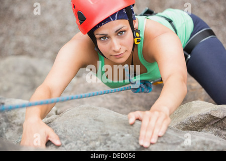 Focused girl climbing rock face Stock Photo