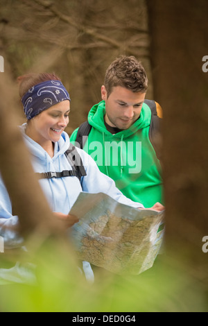 Happy couple standing in a forest reading map Stock Photo