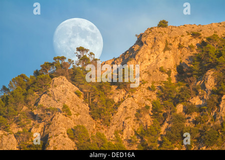 Real full moon rising over Puig des Teix mountain at sunset. Tramuntana mountains, Deia, Majorca, Balearic islands, Spain