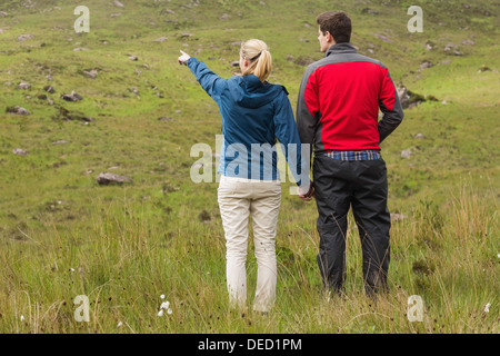 Couple holding hands with woman pointing on a walk Stock Photo