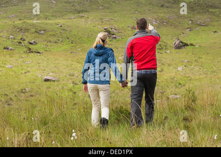 Couple holding hands on walk with man pointing Stock Photo